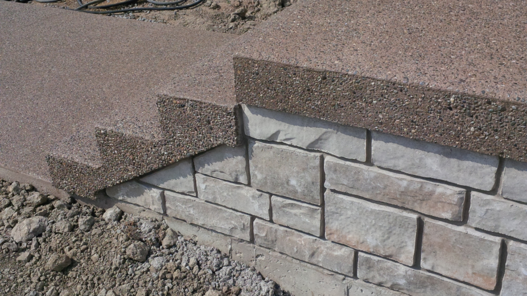 This photo shows a closeup of an outdoor staircase with 4 steps highlighting exposed aggregate concrete.