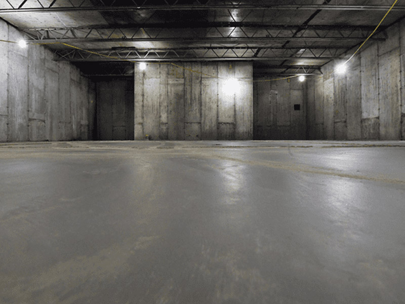 This photo shows a concrete basement floor recently poured surrounded by concrete walls.