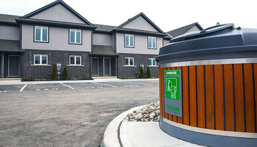 This photo shows a Molok bin in a parking lot in front of some houses.