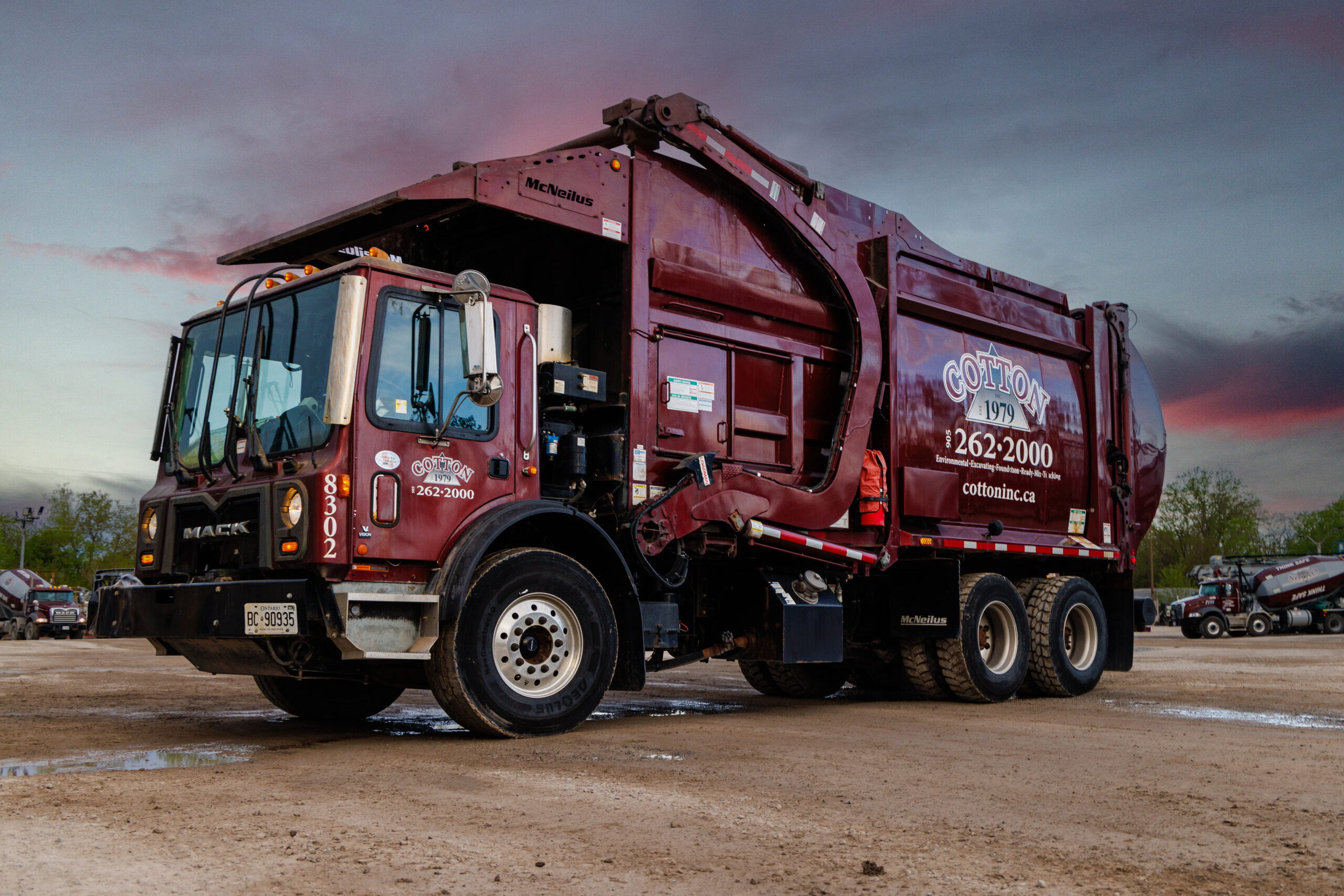 This photo shows a maroon garbage truck with a Cotton Inc logo.