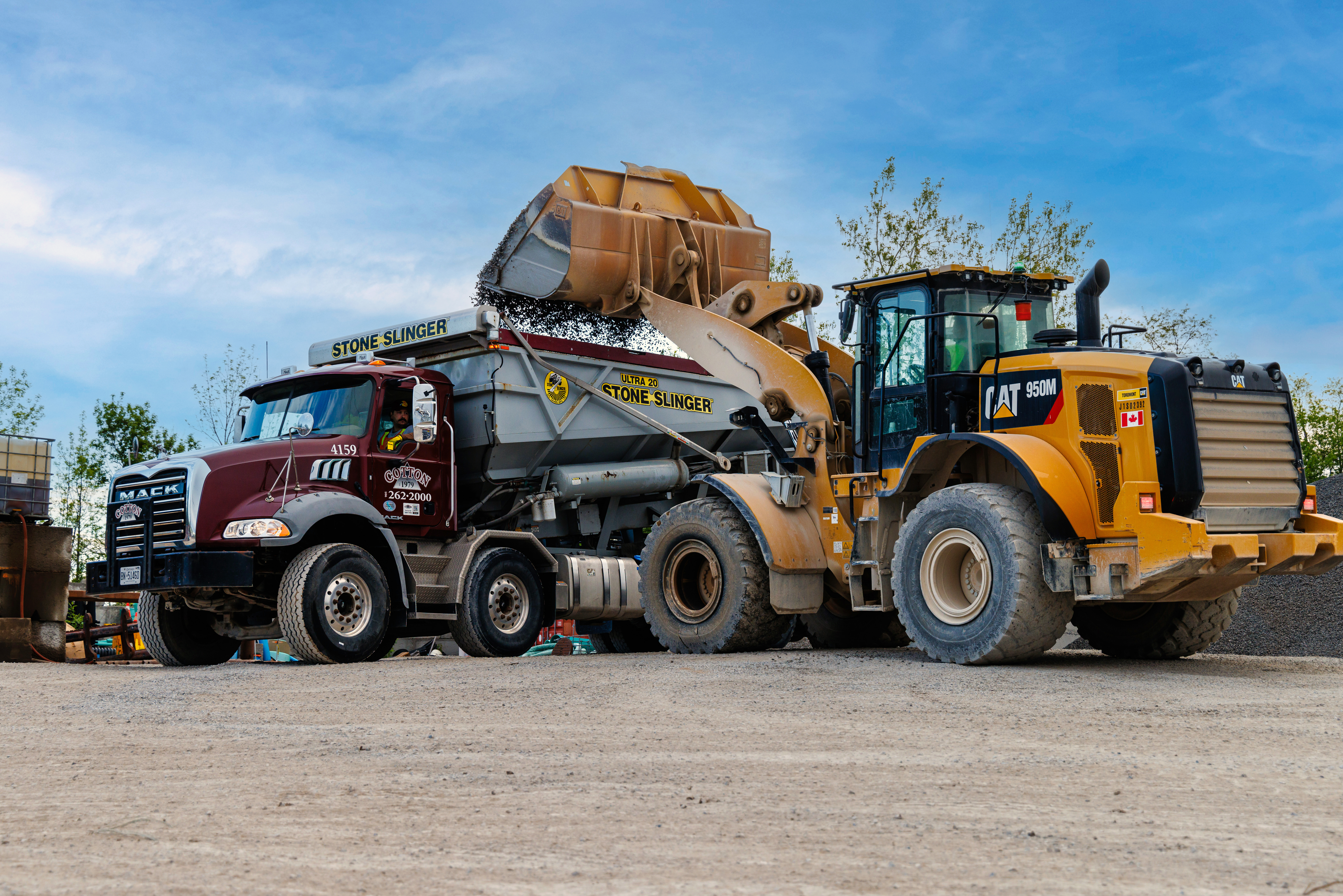 This photo shows a bulldozer dumper stone into a Cotton Inc stone slinger truck.