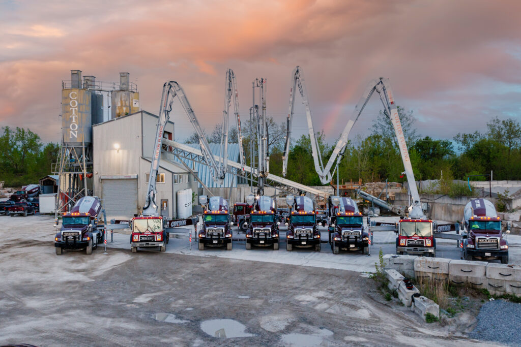 This photo shows several concrete trucks and concrete pump trucks in front of the Cotton Inc. concrete plant.